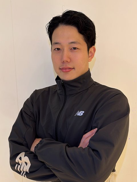 腕を組んで立つトレーナーの槙尾良太